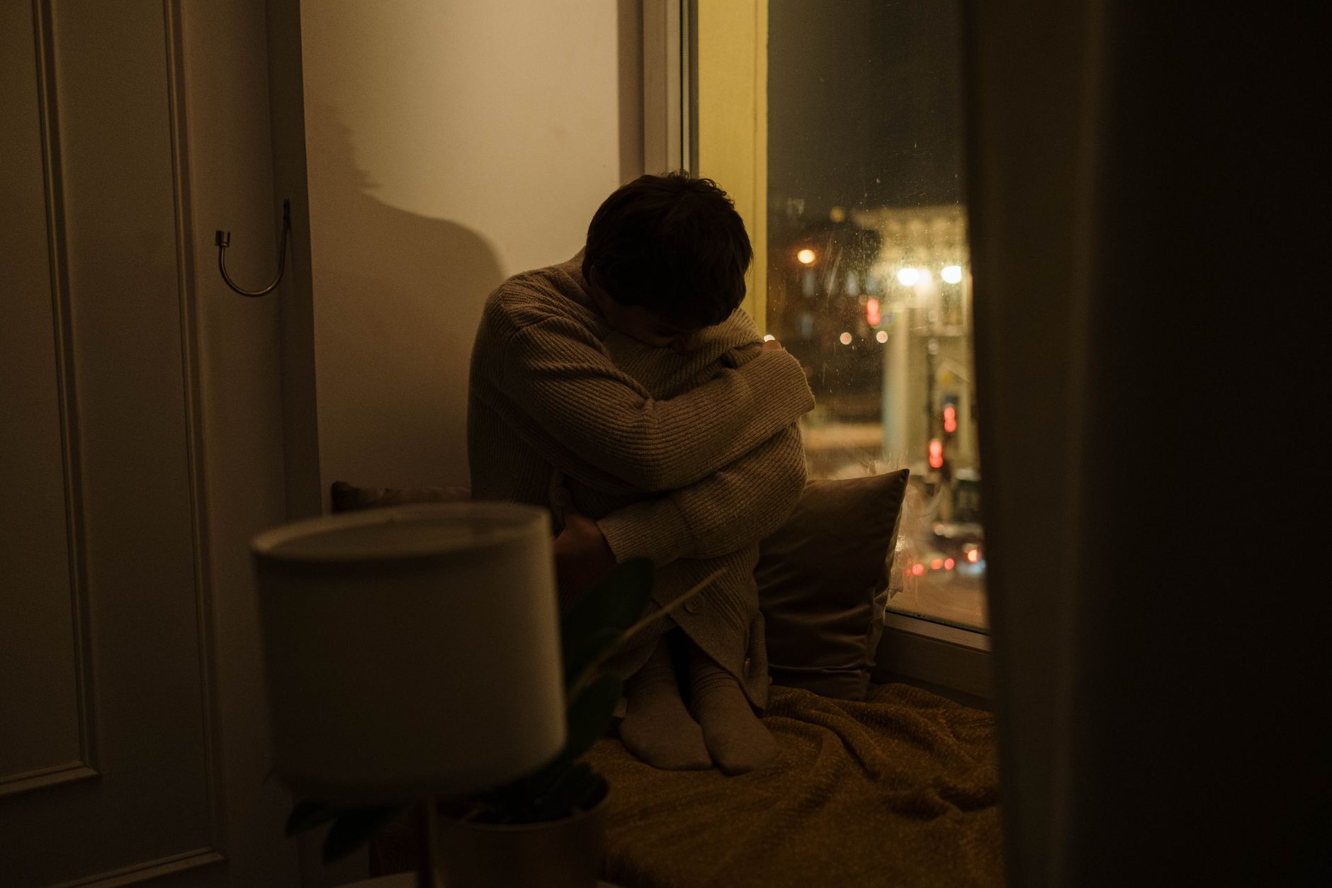 Person sitting alone by a window, thoughtful