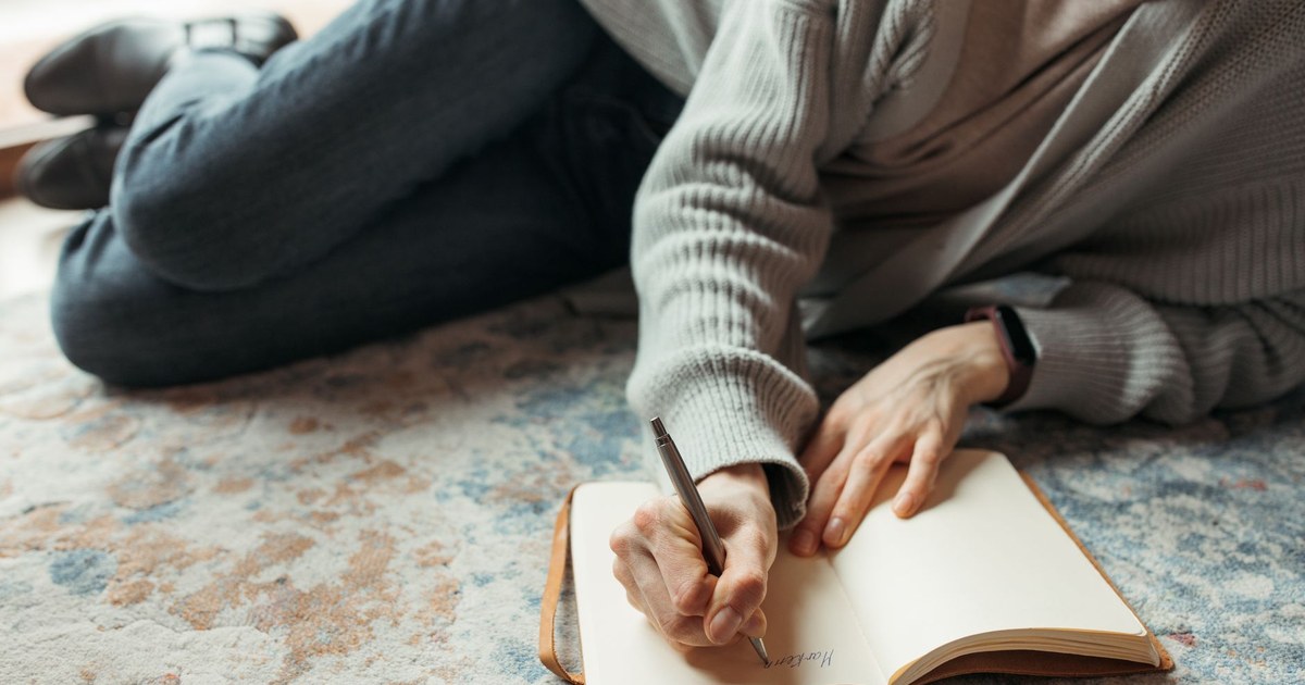 Person writing thoughtfully in a journal at home
