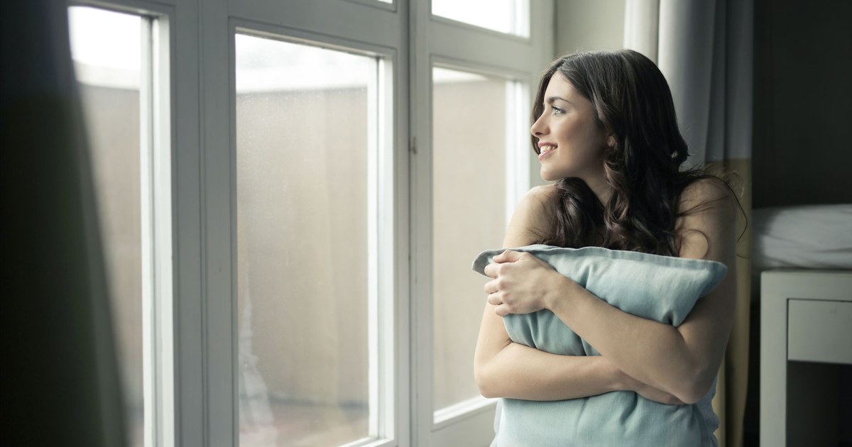 Adult sitting quietly by a window, deep in thought