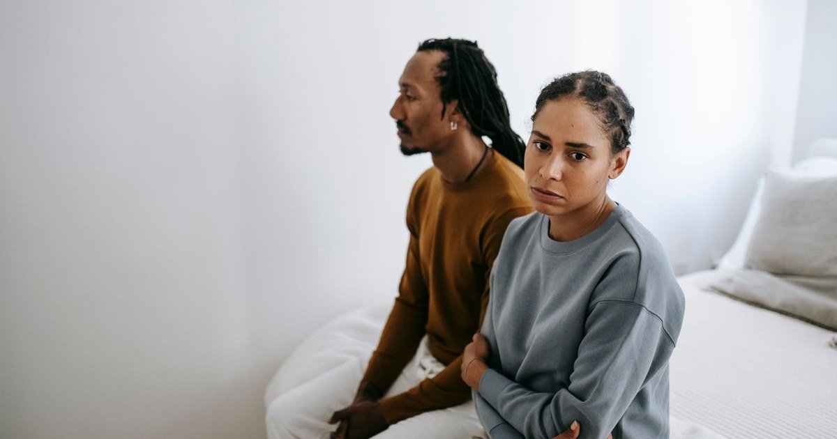 Two people sitting close but looking away from each other, tension between them