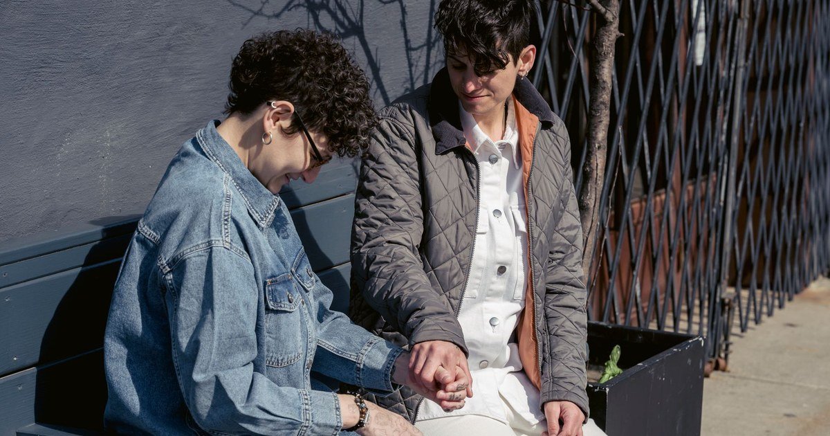 A couple sitting close together, talking warmly and holding hands