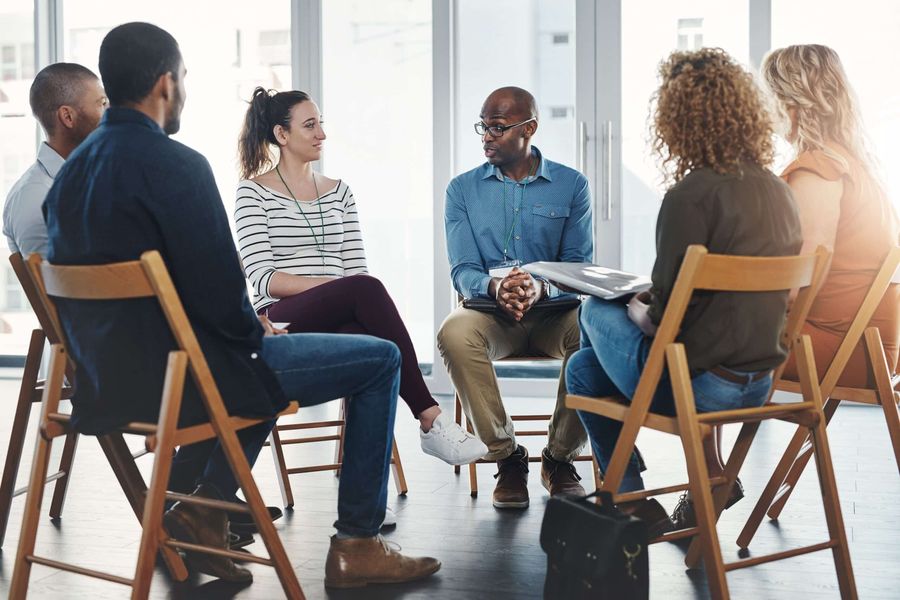 Group therapy session with participants seated in a circle discussing